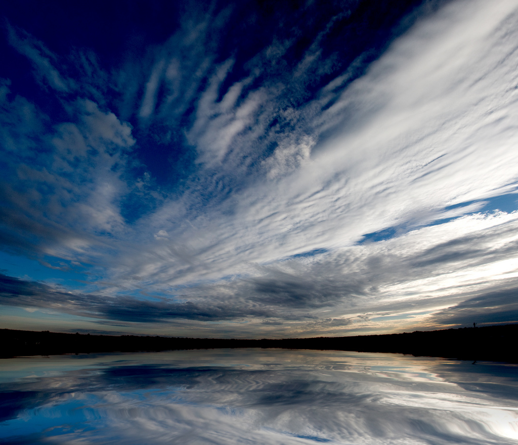 Fish-eye lens picture of rippling clouds in a deep blue sky reflected in still water