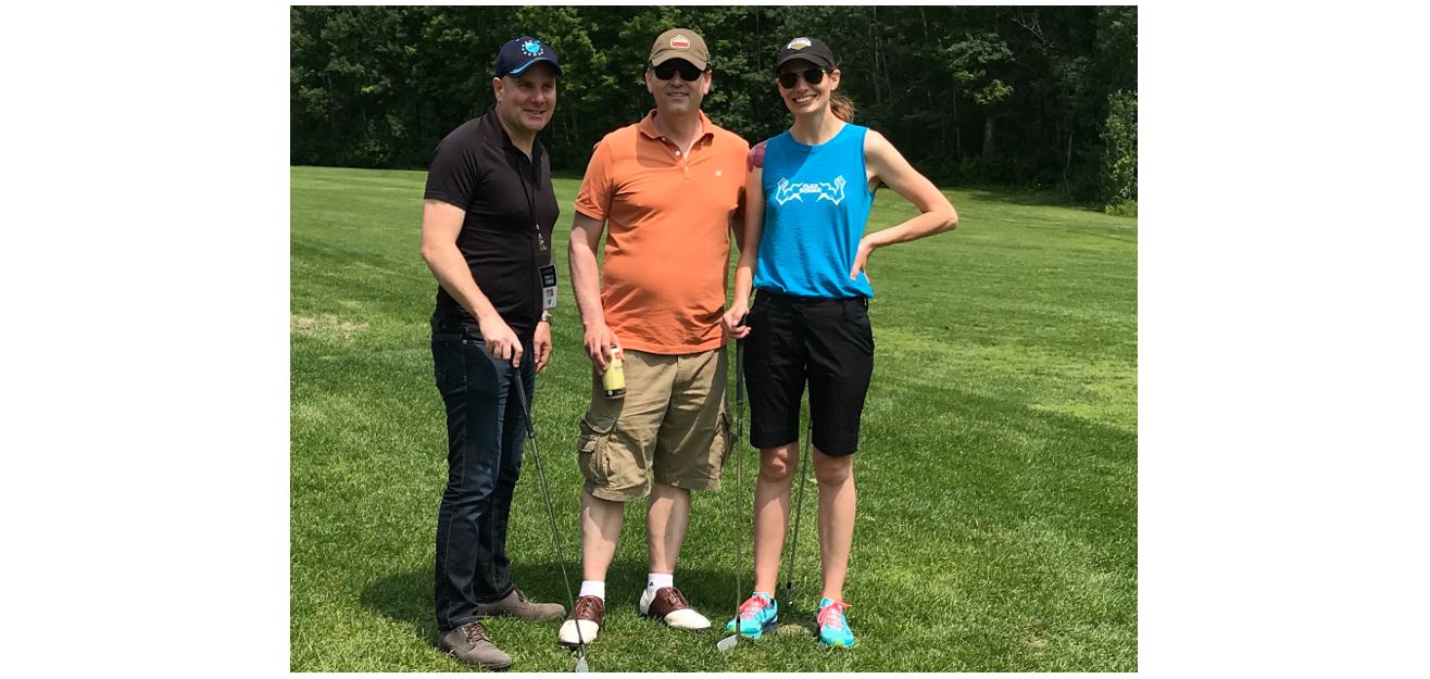 Three smiling people in sunglasses on the green